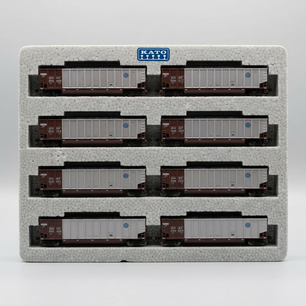 Six N-scale model freight cars arranged in two rows on a gray foam display block, photographed from above on a tan textured surface.
